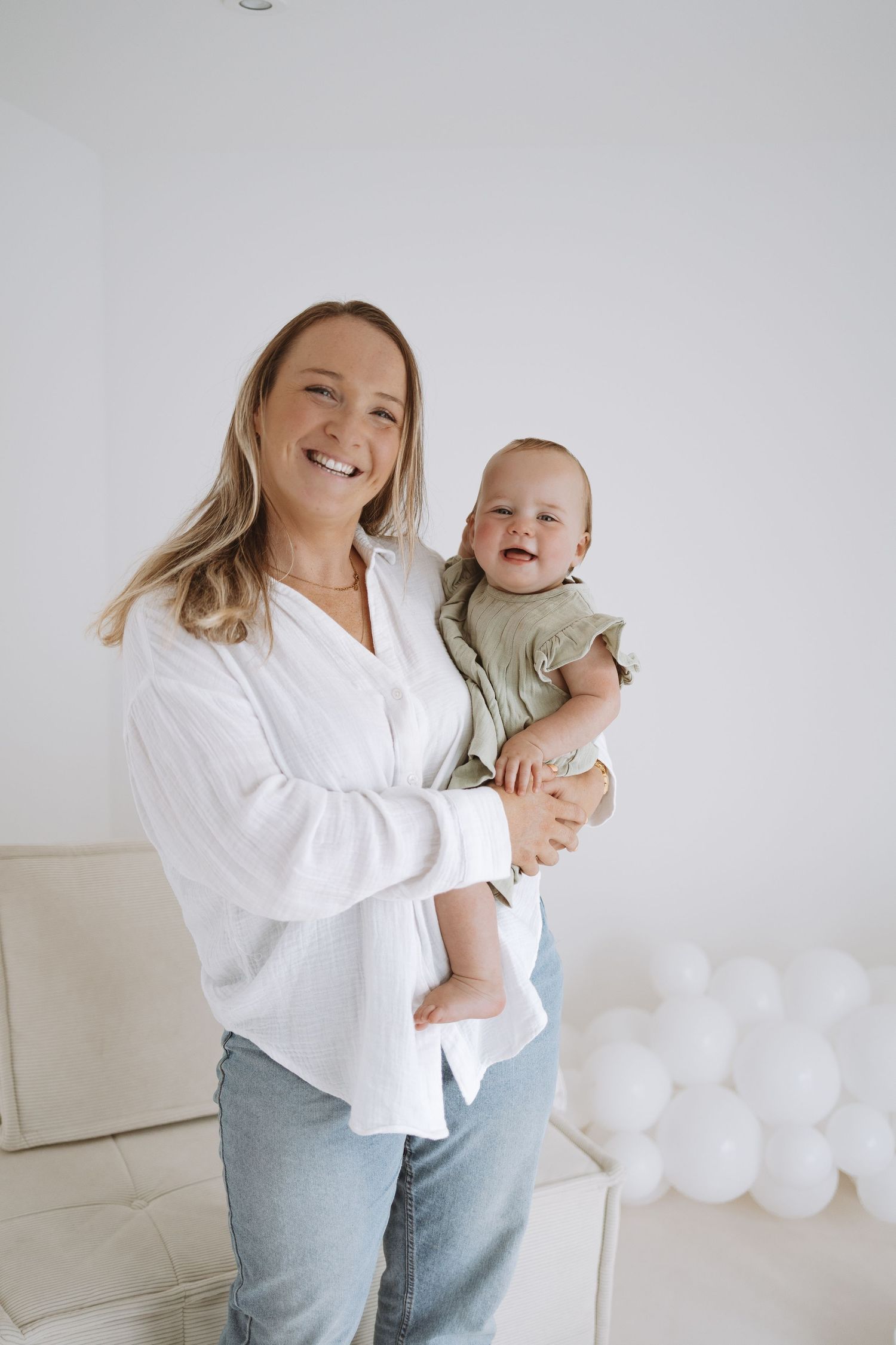 Black and white photo of a parent and child sharing a joyful moment while sitting on a white chair.