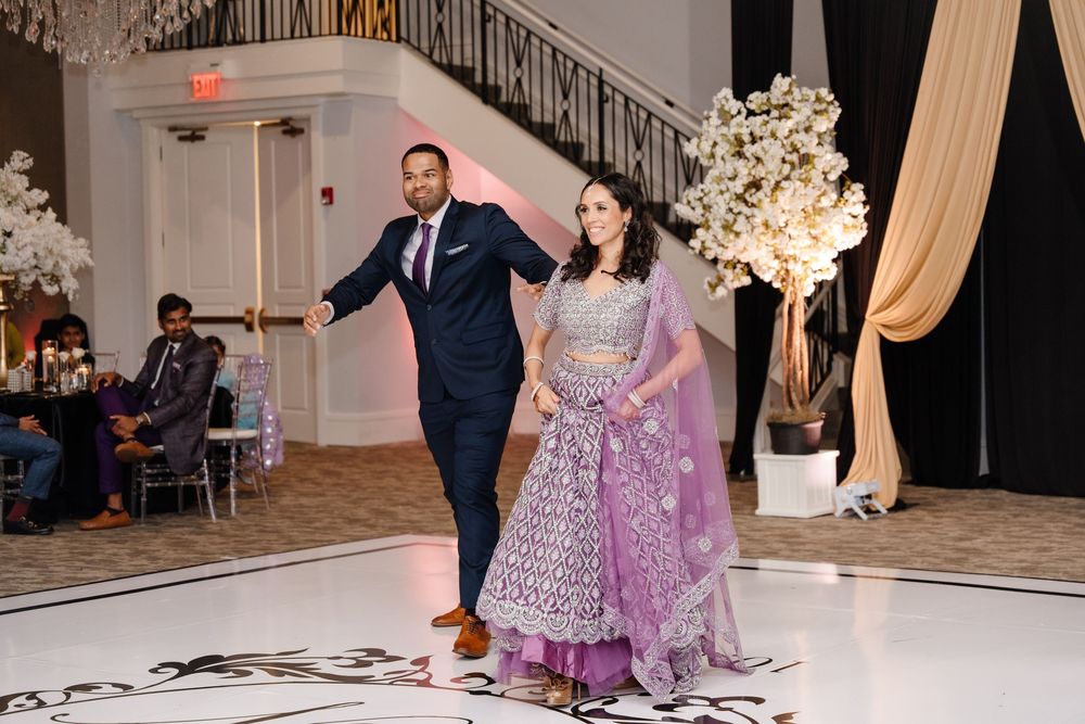 South Asian couple making grand entrance at wedding reception, bride wearing lavender embroidered lehenga.