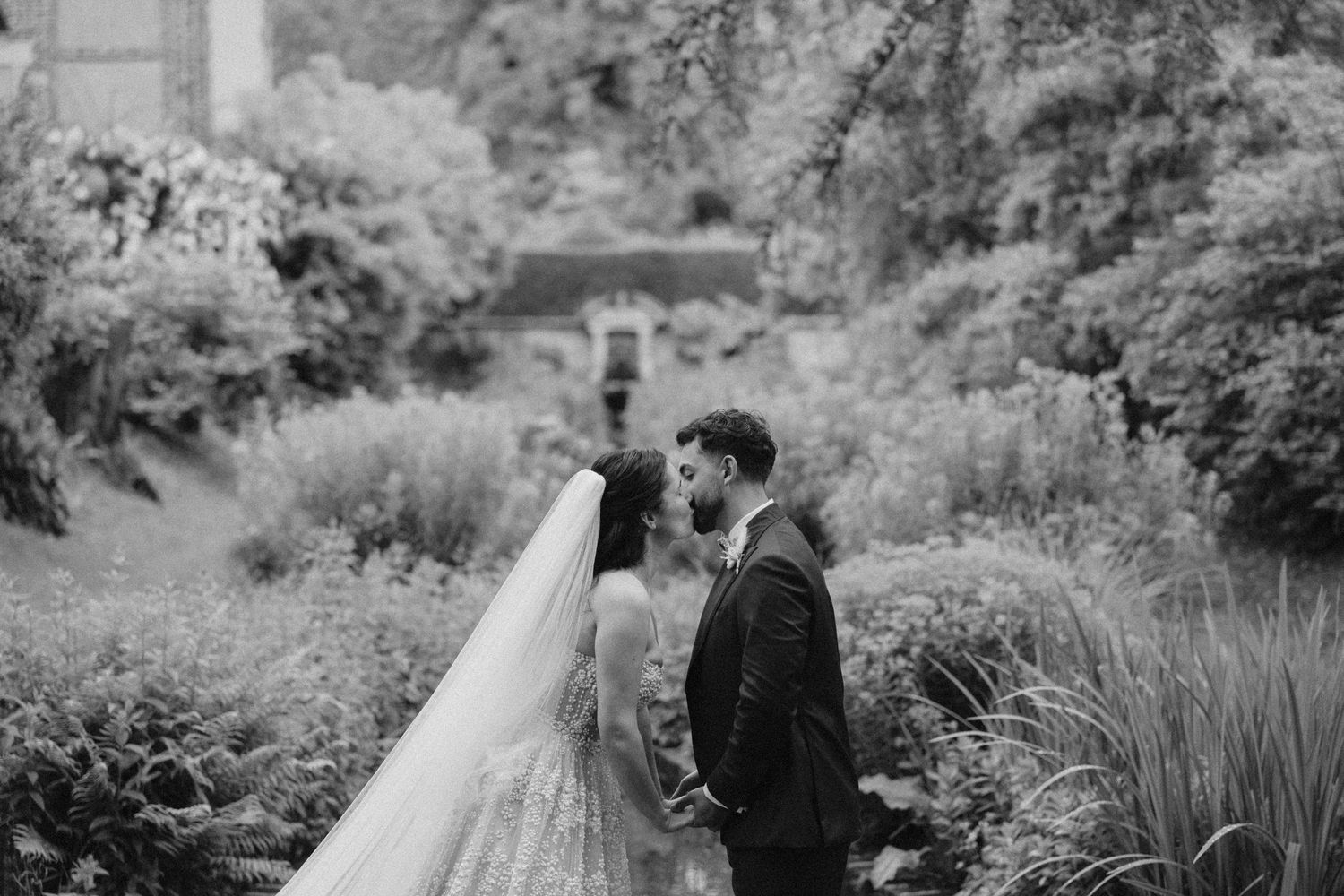 Black and white wedding portraits in lush garden setting.