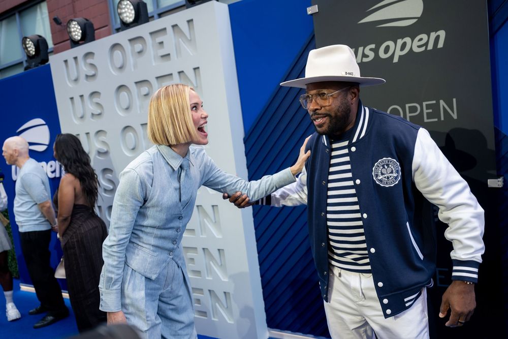 Two stylish guests pose and laugh at the US Open tennis tournament on the blue carpet event.