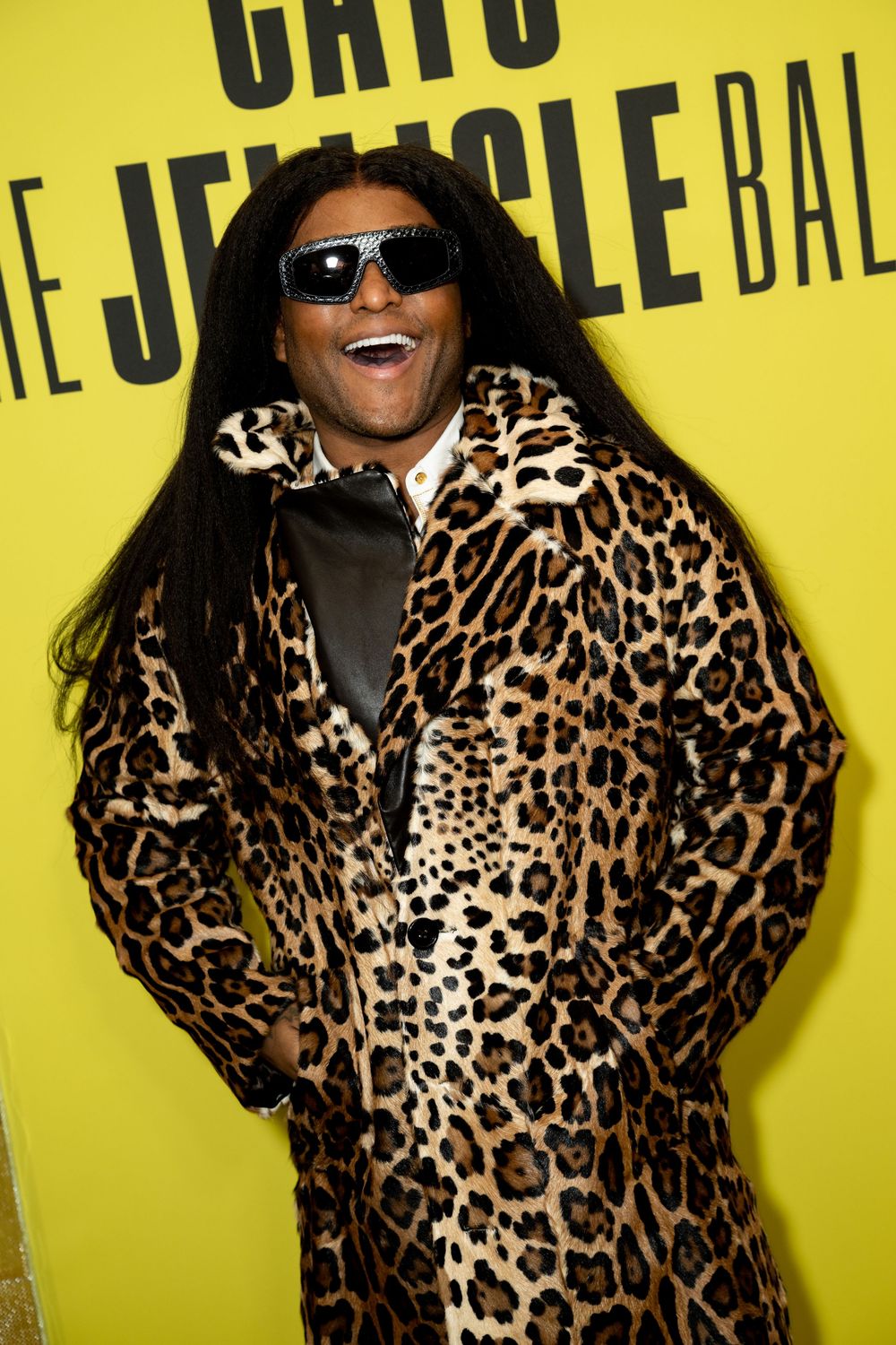 Person wearing leopard print fur coat and sunglasses with long black hair posing at The Jungle Ball event.