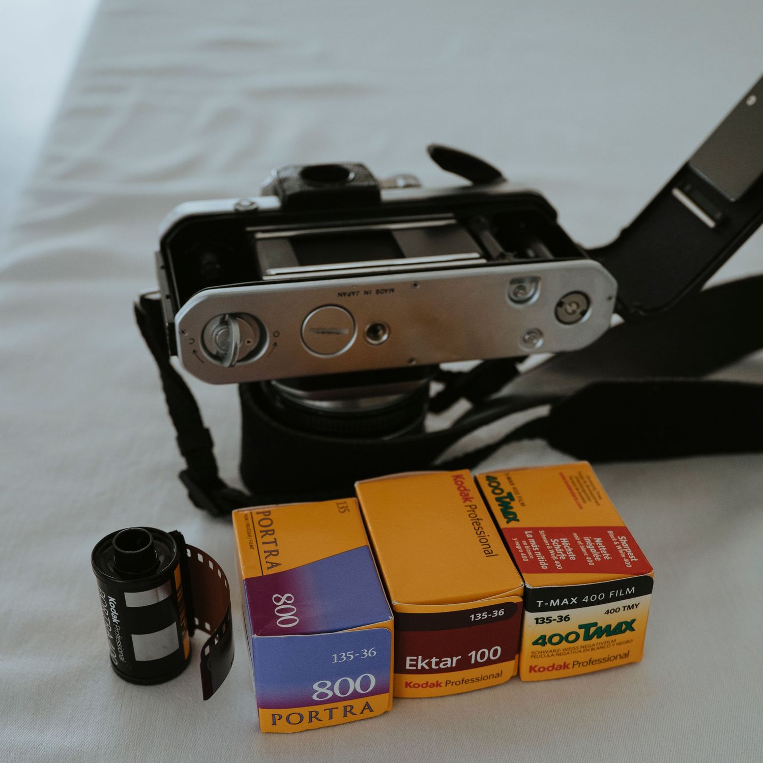 Vintage film camera with Portra 800 and Ektar 100 film boxes displayed on white background.