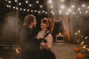 A romantic evening wedding celebration under glowing string lights with couples dancing and embracing.