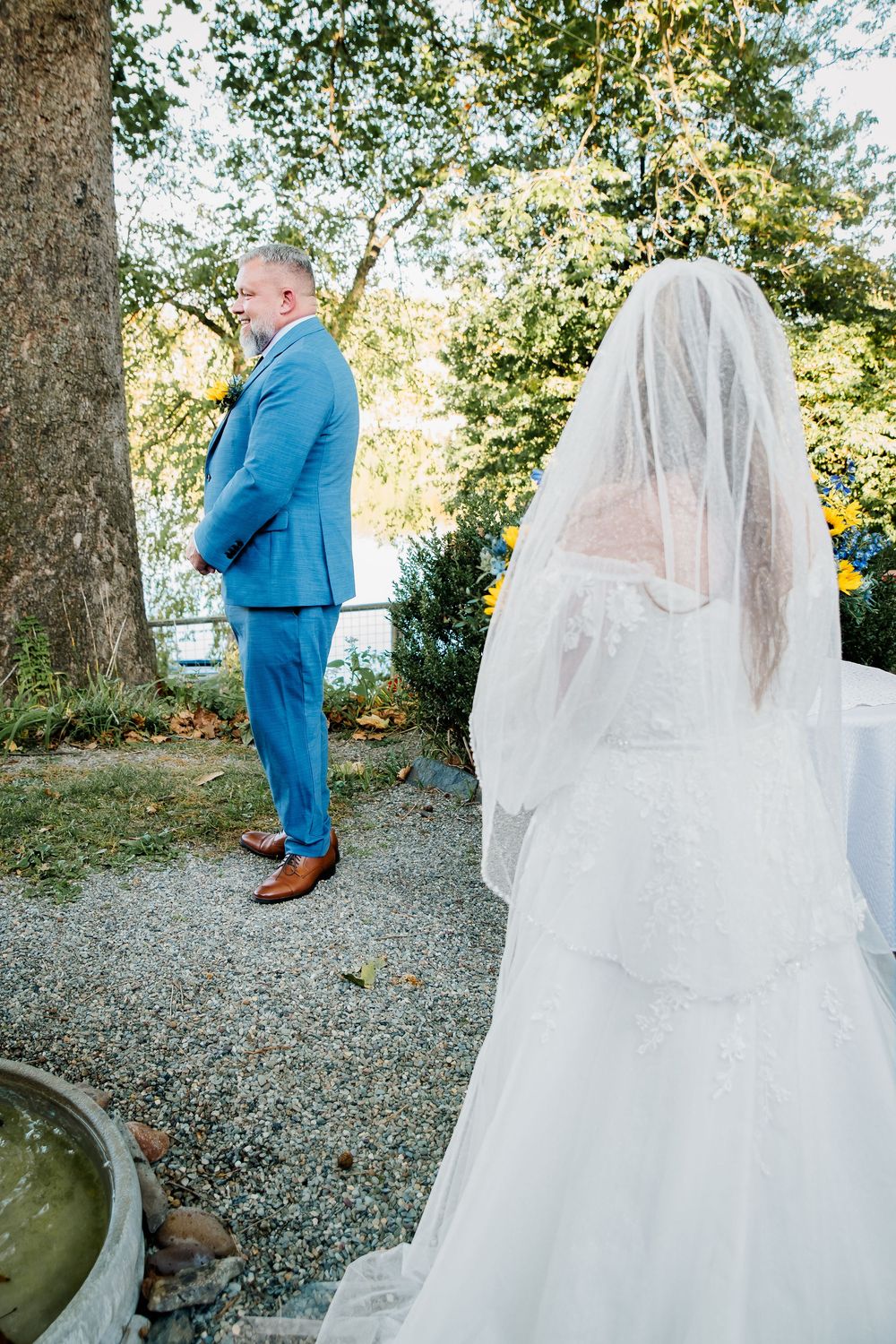 A touching first look wedding moment between a person in a bright blue suit and a bride in a flowing white gown and veil.