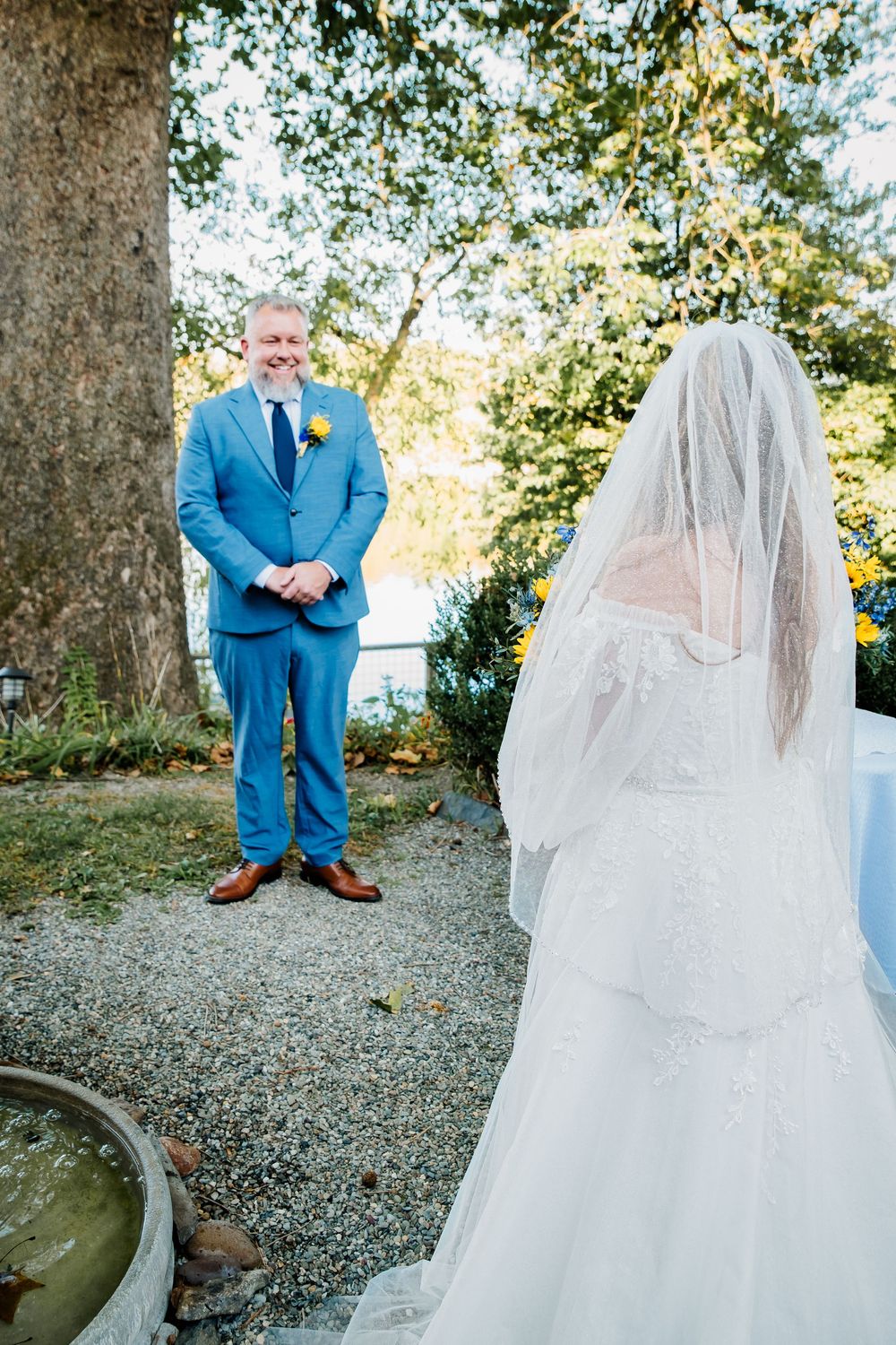 Candid outdoor wedding moment showing interaction between bright blue suit and delicate white wedding dress.