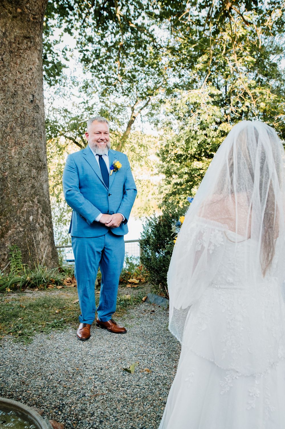 First look wedding photography sequence showing bright blue suit and elegant white bridal gown outdoors.
