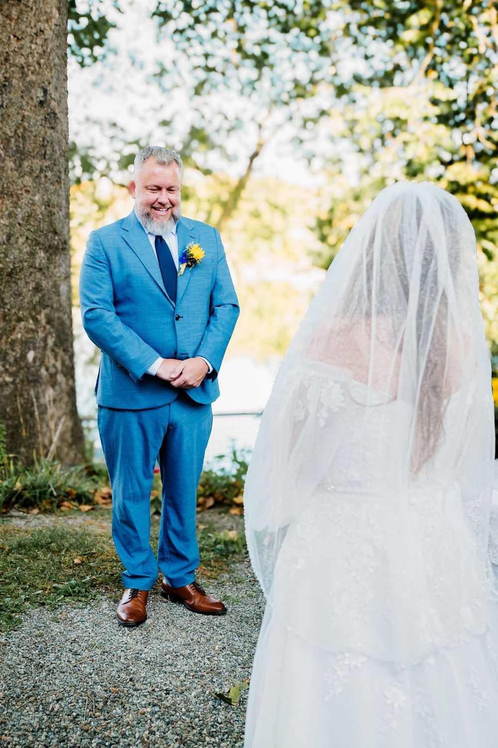 Garden wedding scene featuring bright blue formal suit and elegant white bridal gown with veil.