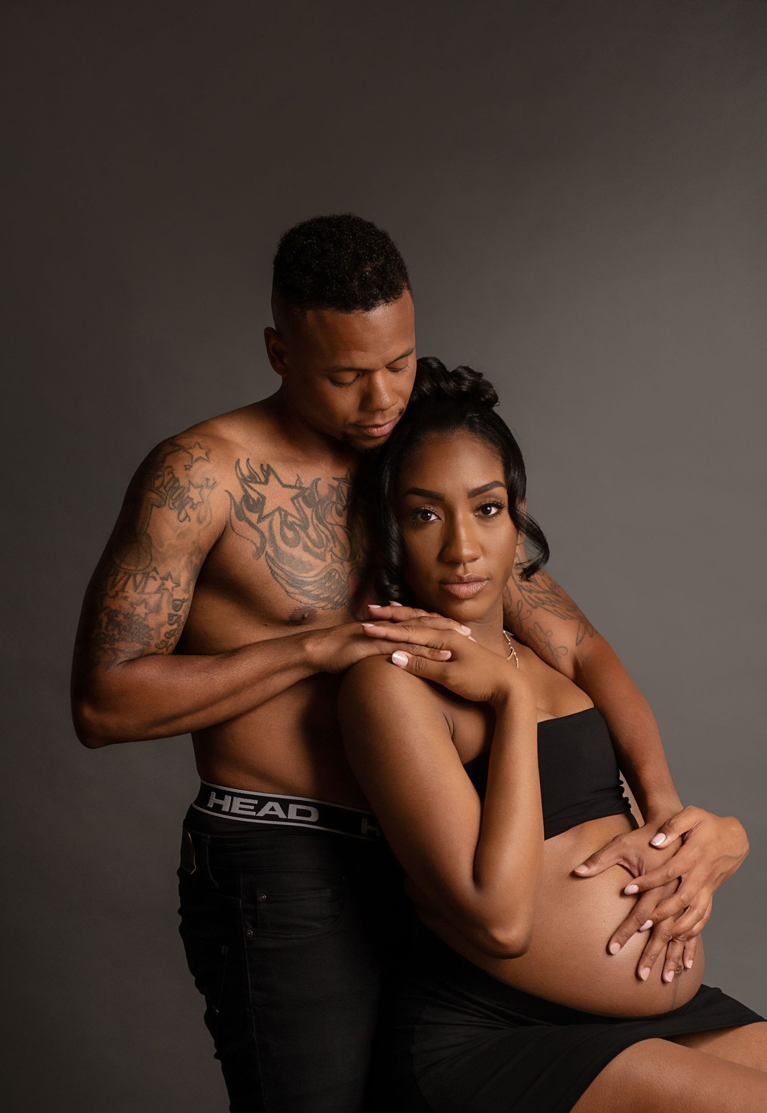Intimate couple photography session with artistic lighting and dramatic poses against dark background.