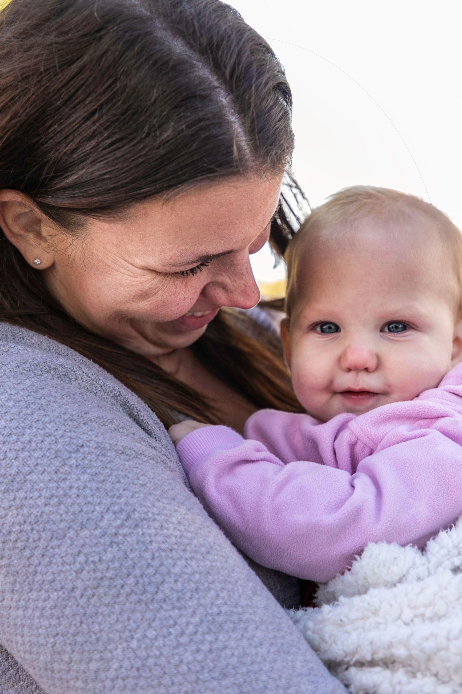 a close up of a mom looking at her young daughter, while the daughter looks at the camera