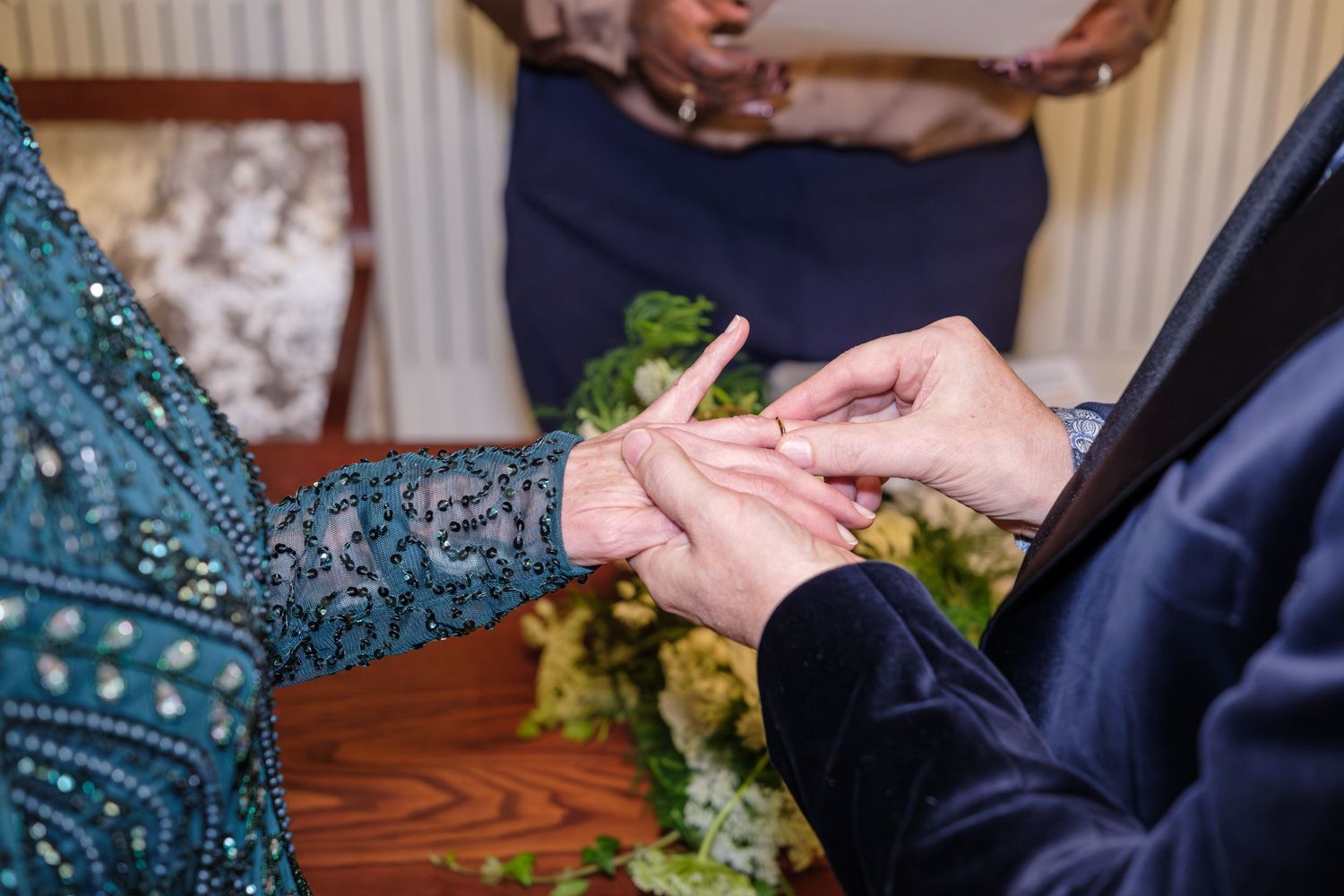 Close-up view of hands exchanging a small green plant or seedling during a gardening activity.