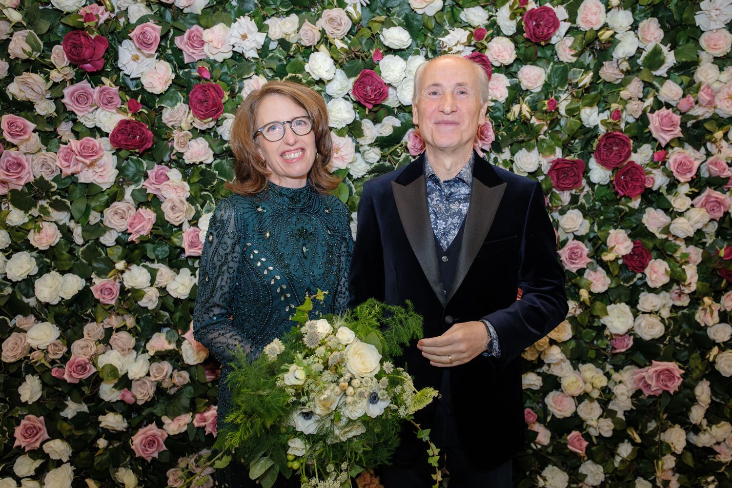 A floral backdrop with pink and white roses creates an elegant setting for a formal event.