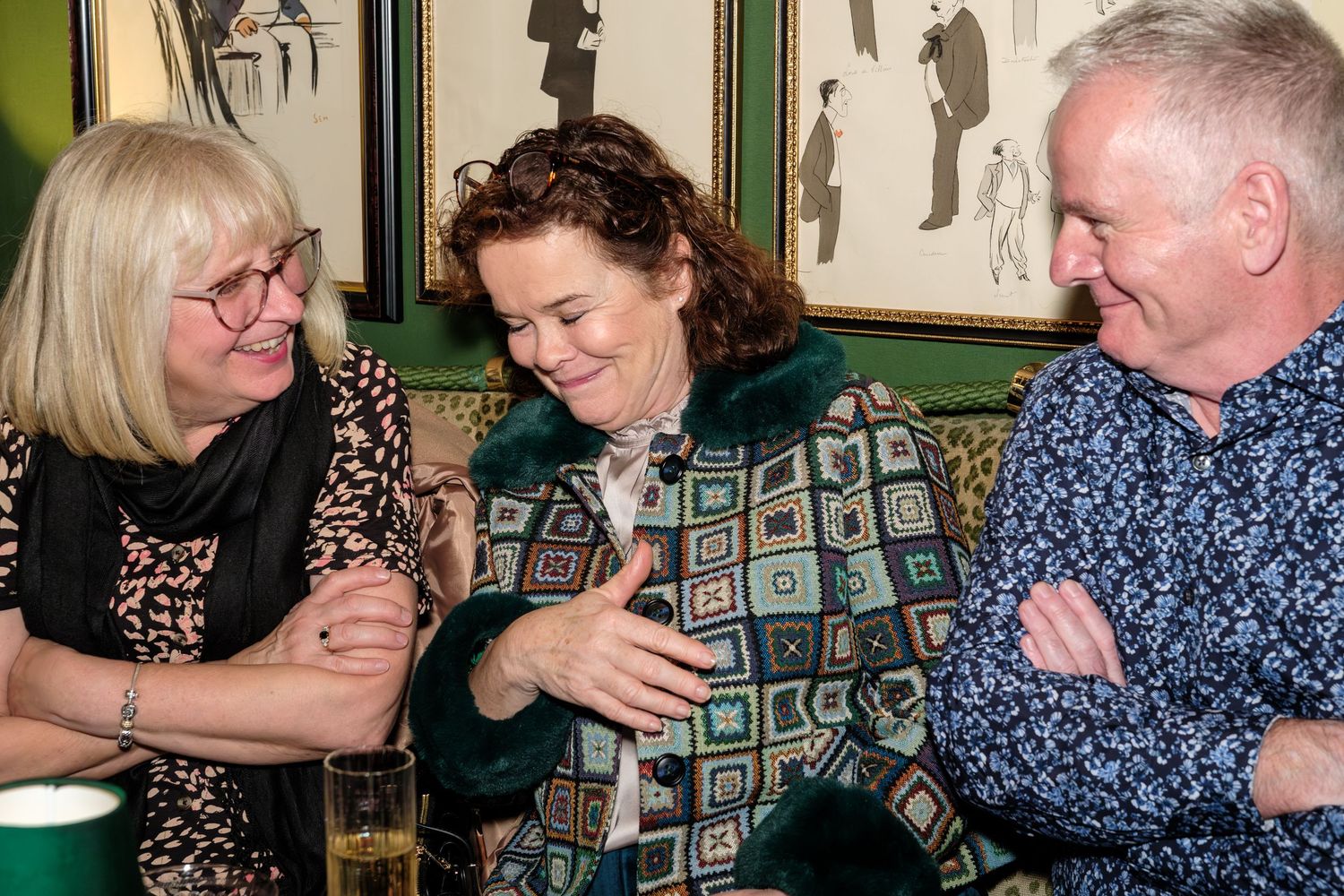 A group of people sitting at a table sharing laughter and conversation in a casual dining setting.