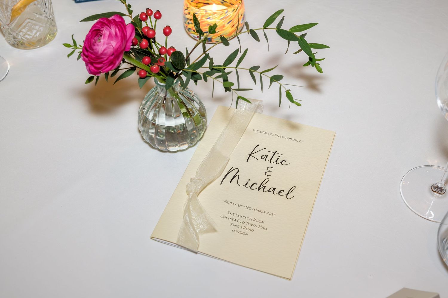 Wedding place card settings with elegant calligraphy names displayed alongside delicate floral arrangements and glassware.
