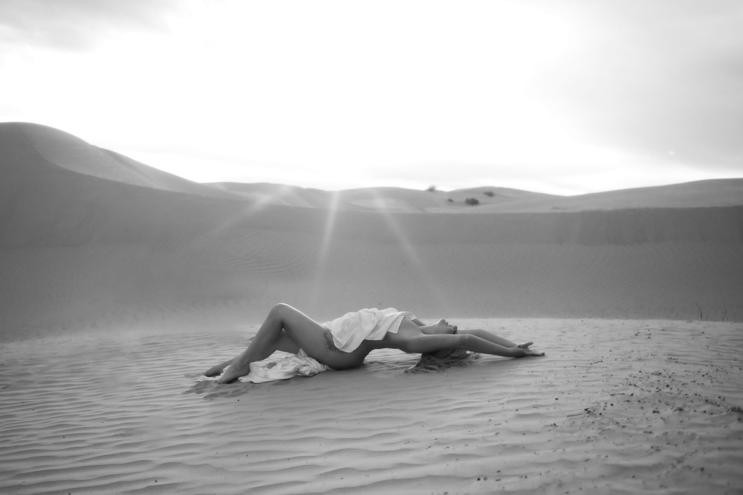 Little Sahara Desert Boudoir Photo of woman posing with sunlit bokeh falling near her.