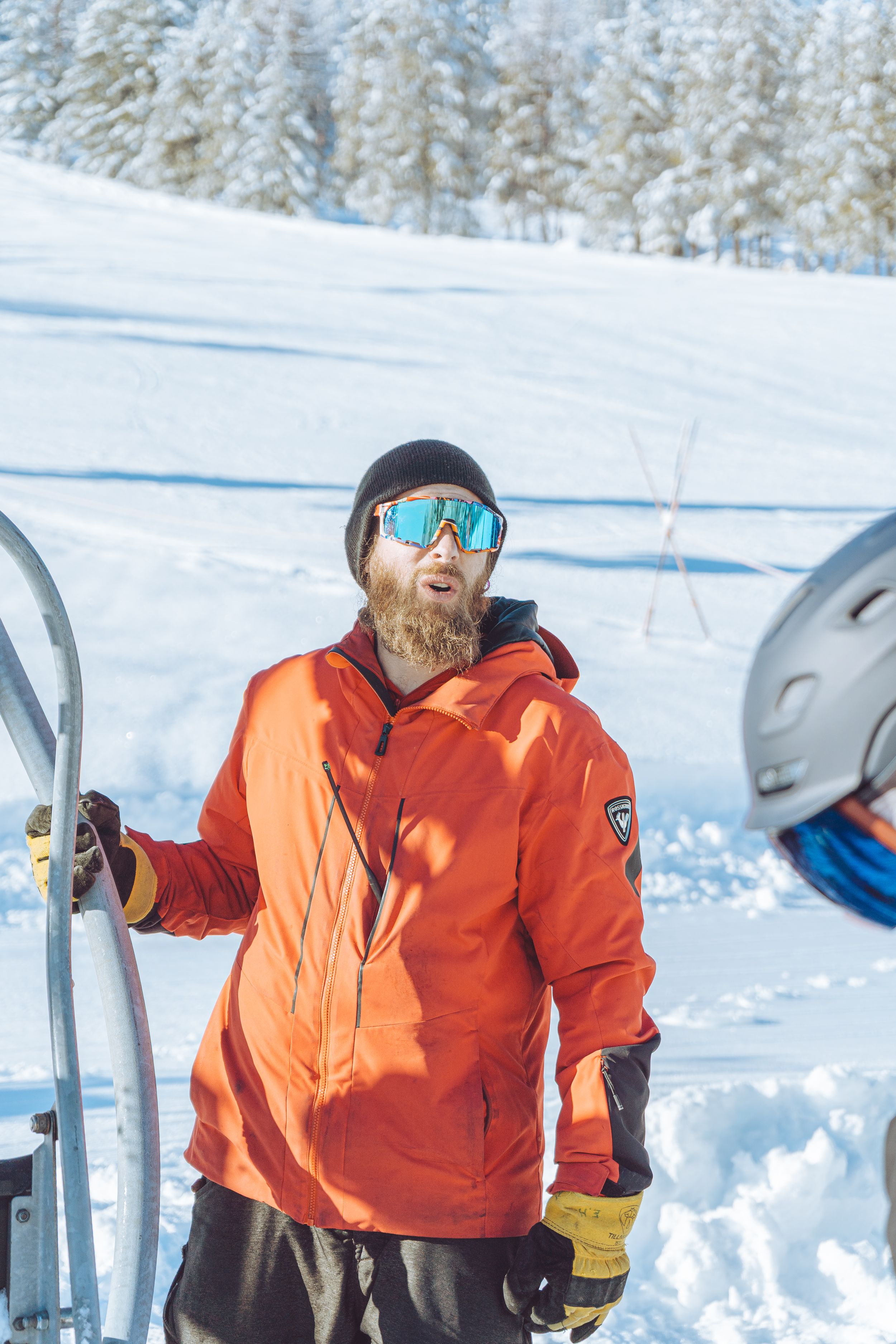 Ski patrol member in bright orange jacket working in snowy winter conditions.