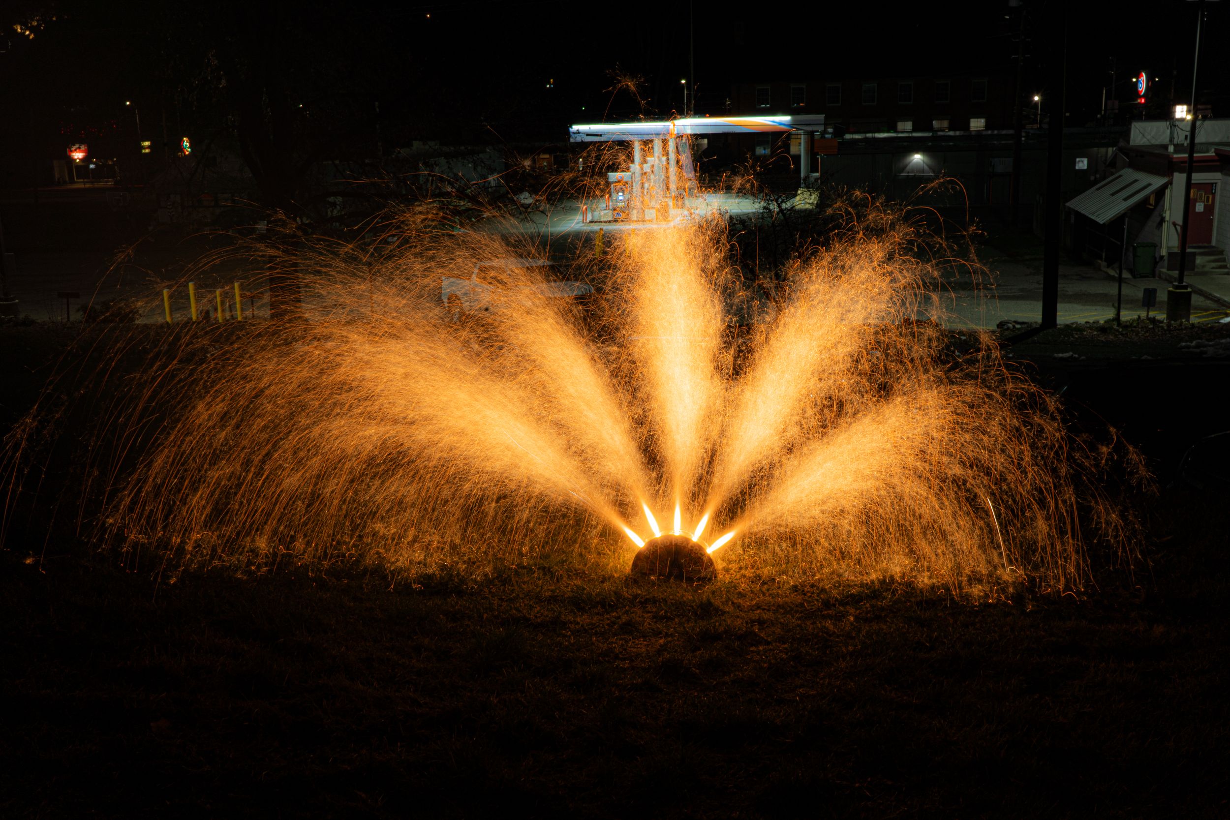 Golden fountain water display illuminated at night creating symmetrical spray patterns.