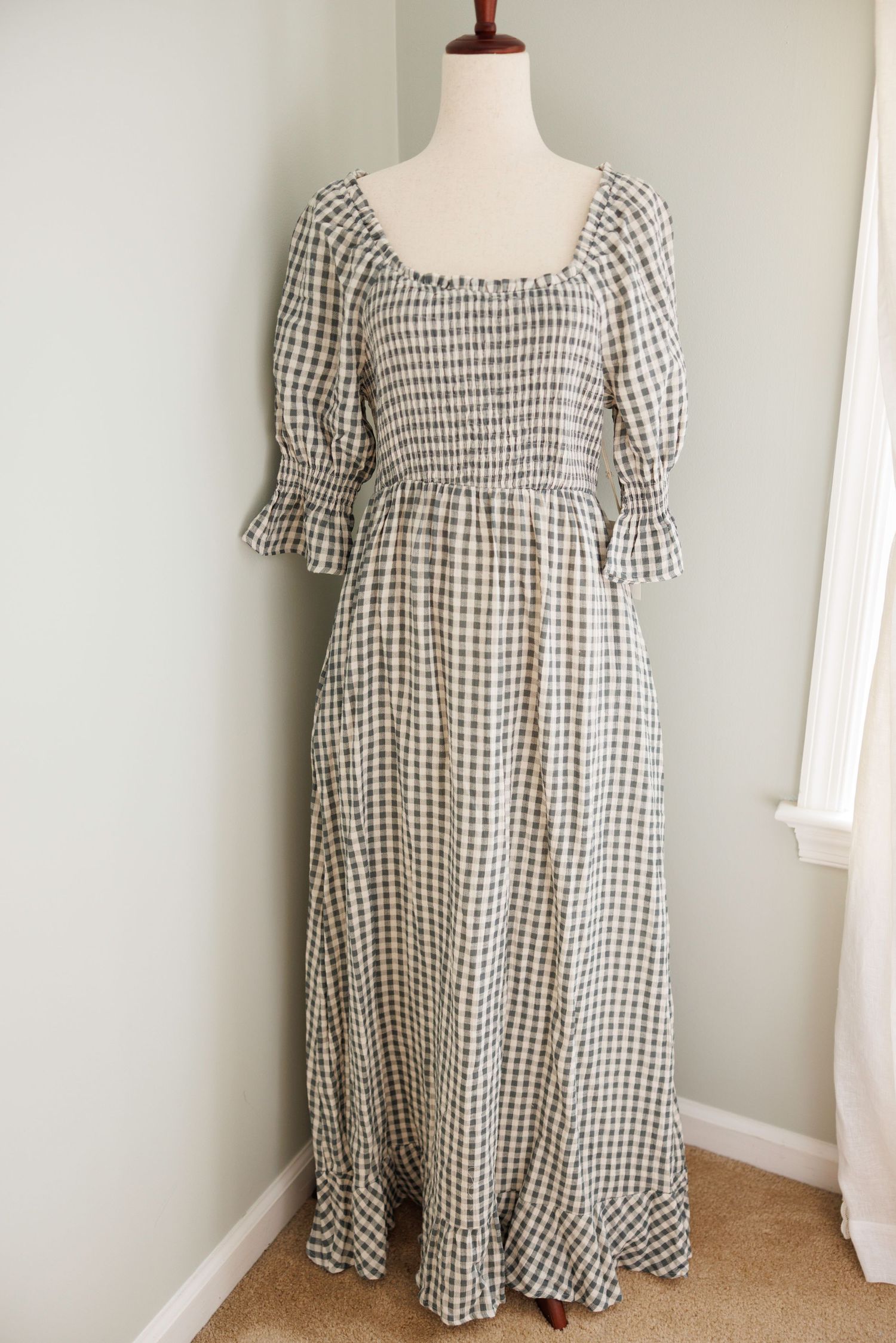 Vintage cream-colored maxi dress with puff sleeves and gathered neckline displayed on white mannequin against pale wall.