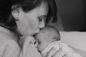 maman qui embrasse le front de son nouveau-né pendant un reportage photo dans les yvelines