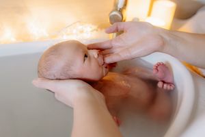 bébé qui tète le doigt de sa maman pendant une séance photo thalasso bain bébé dans les yvelines