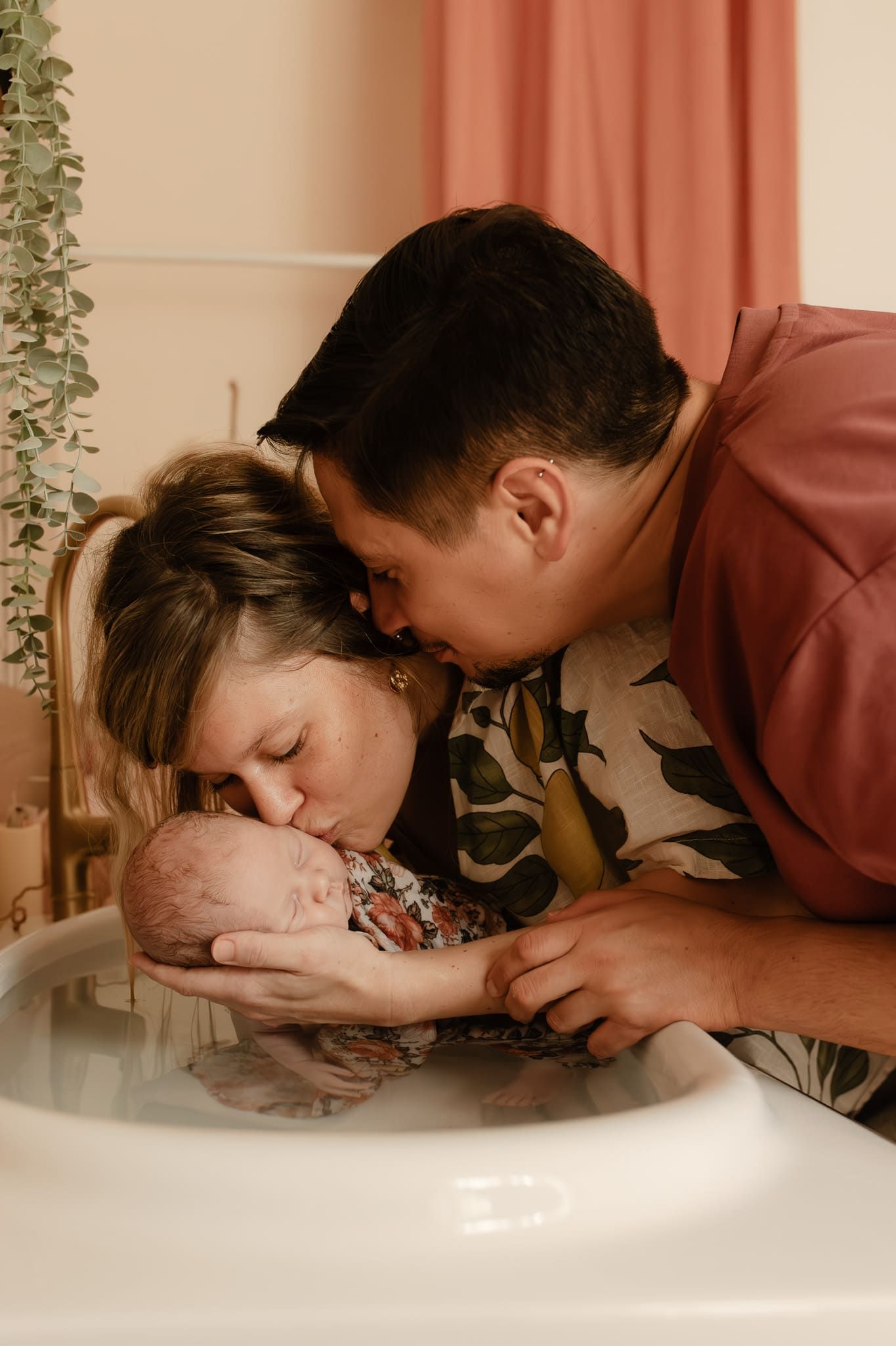 couple qui embrasse leur bébé pendant une séance thalasso bain bébé yvelines