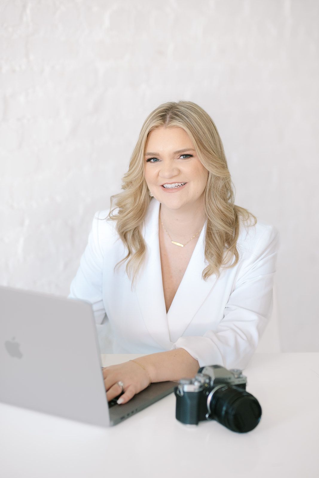 Person in all white outfit sits and poses elegantly against light background in studio photoshoot series.