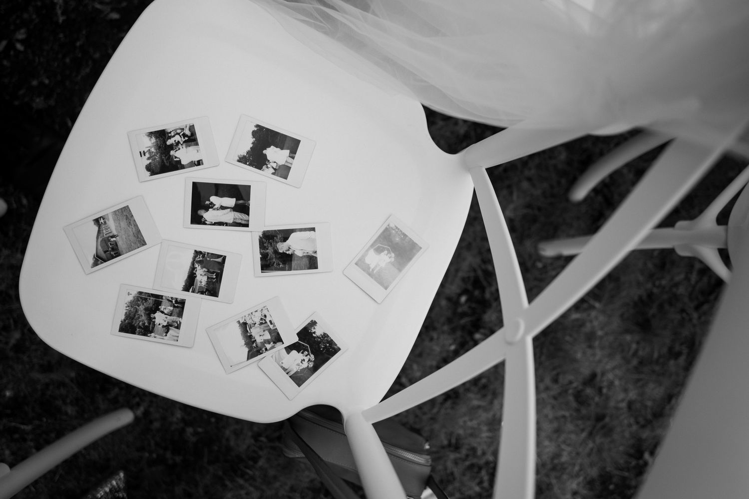 Black and white photograph of vintage polaroid photos arranged on a white chair.