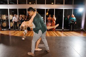 Dancers perform energetic swing dance moves on a wooden dance floor during a lively social dance event.