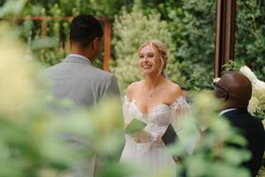 A joyful wedding ceremony takes place outdoors with lush greenery in the background.