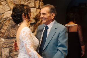 A tender moment shared between two people at a wedding ceremony with stone walls in the background.