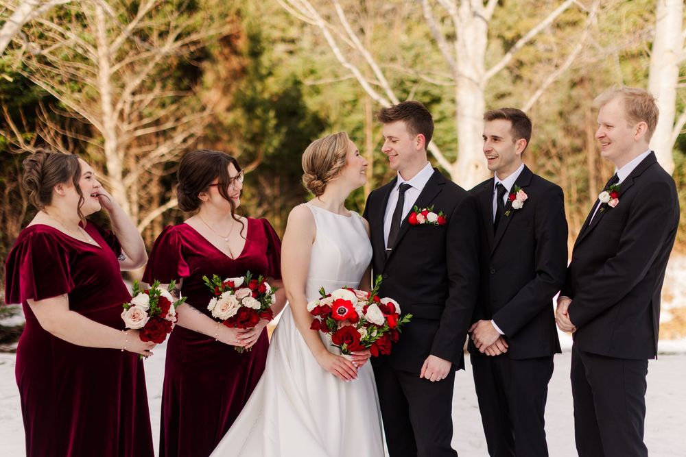 Wedding party members share joyful moments together against a snowy outdoor backdrop.
