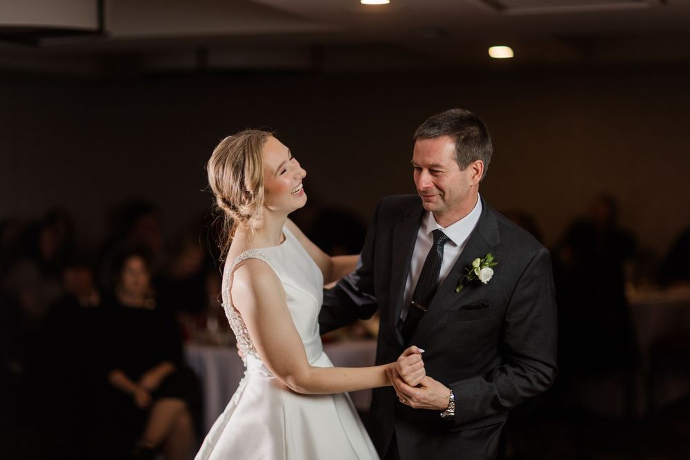 A couple shares their first dance at a wedding reception in a dimly lit ballroom.