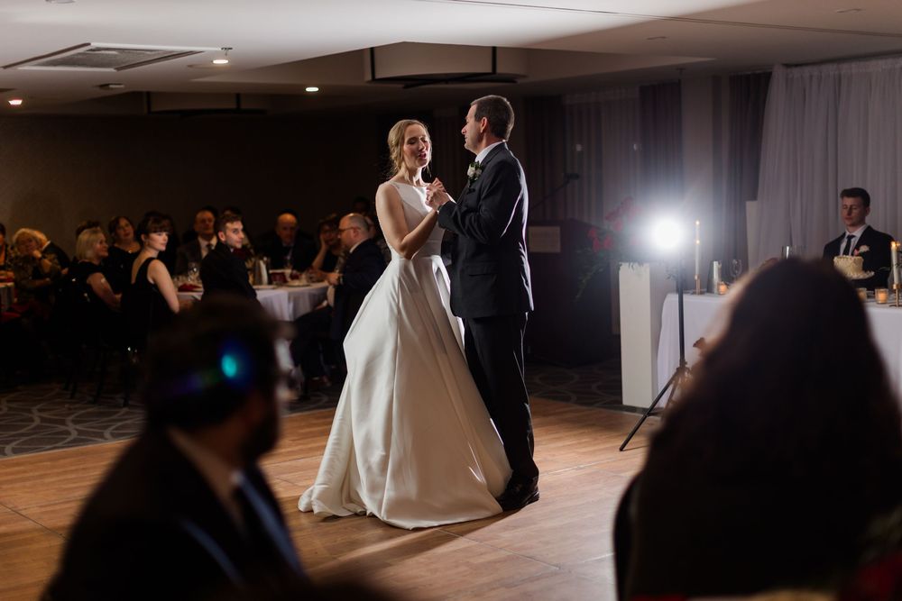 A couple shares their first dance as newlyweds on a dimly lit dance floor at their wedding reception.