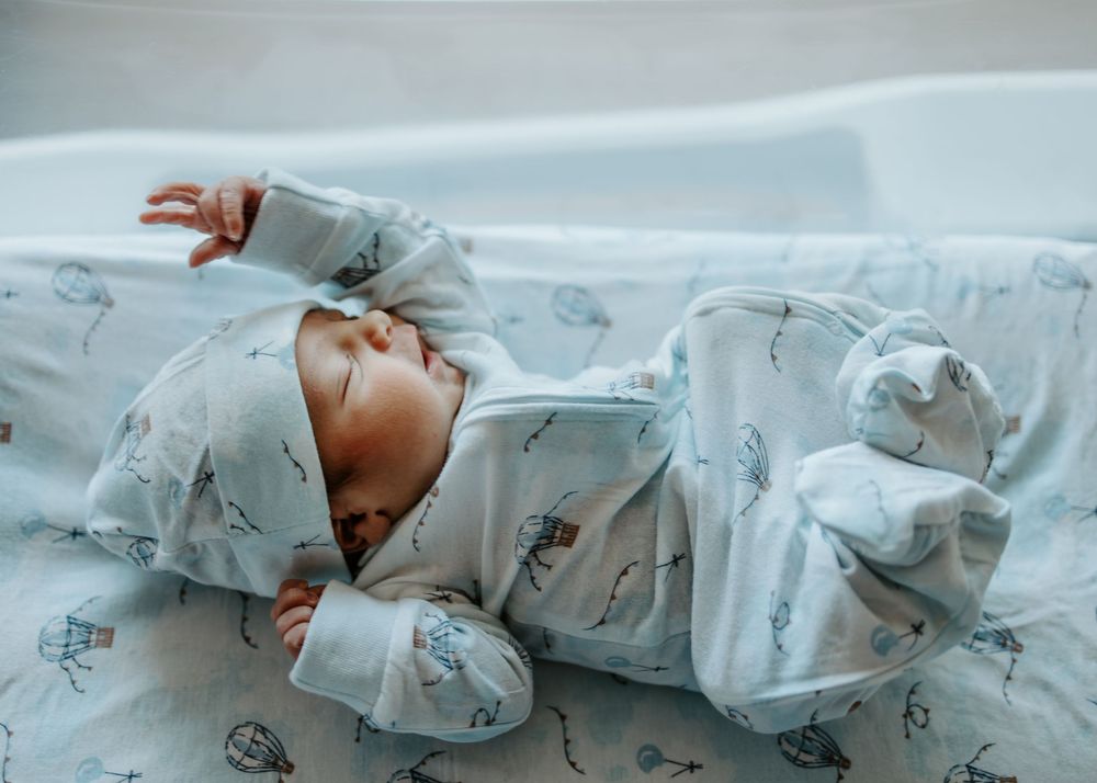 Newborn baby sleeping peacefully in patterned swaddle blanket.