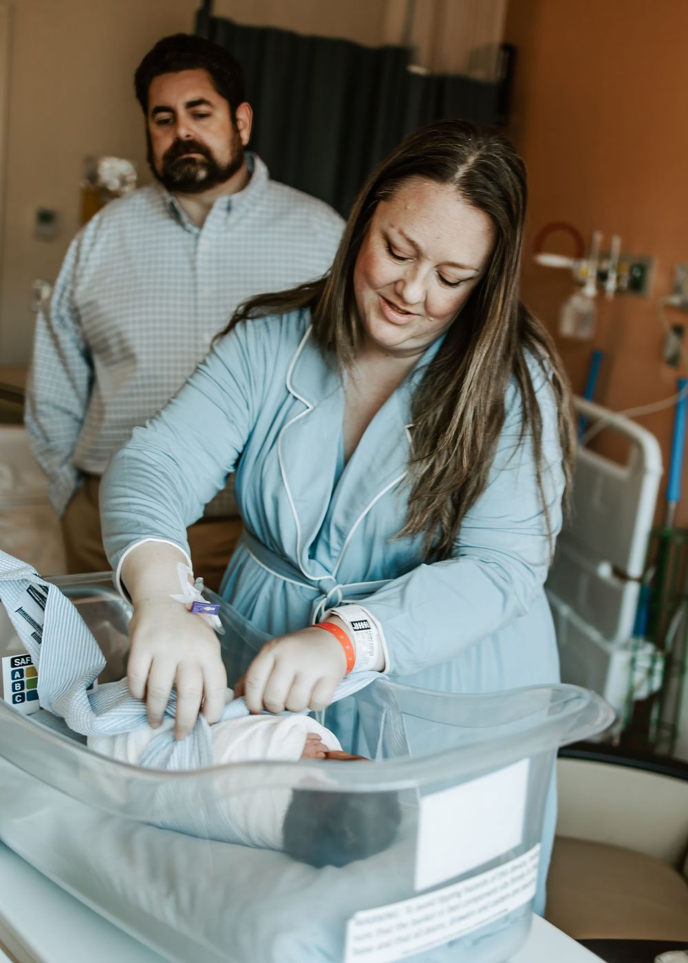 Hospital newborn care session showing gentle moments with baby bassinet.