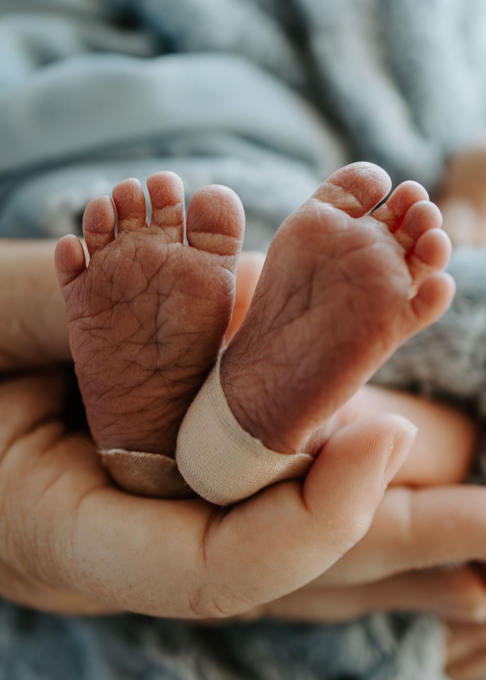 Close-up of tiny newborn baby feet showing delicate wrinkles and creases.