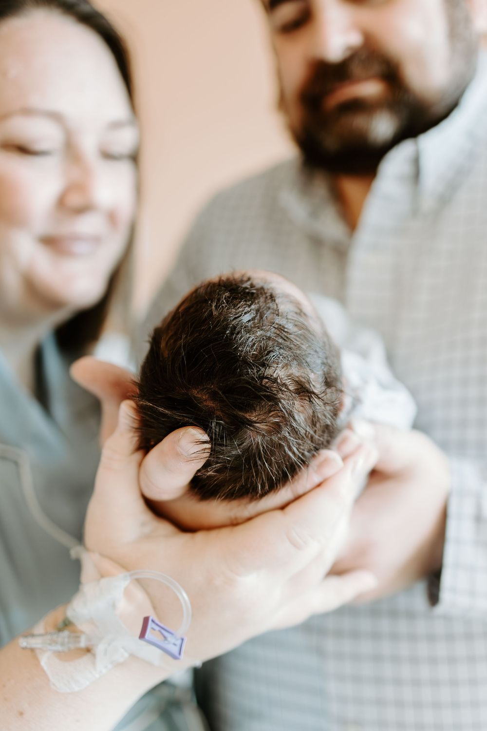 New parents share an intimate moment while holding their newborn baby.