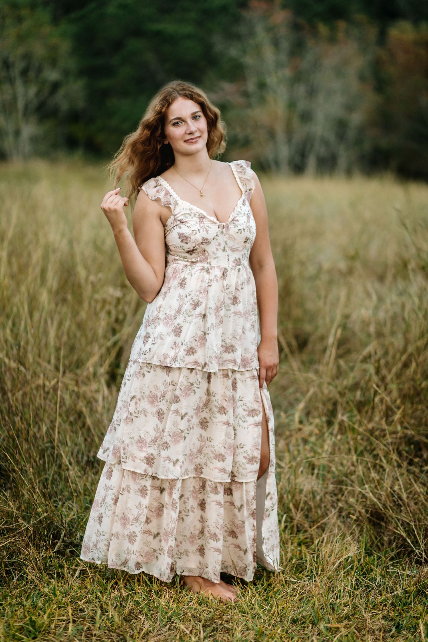 A floral dress flows gracefully in a field of tall grass during a summer photoshoot.