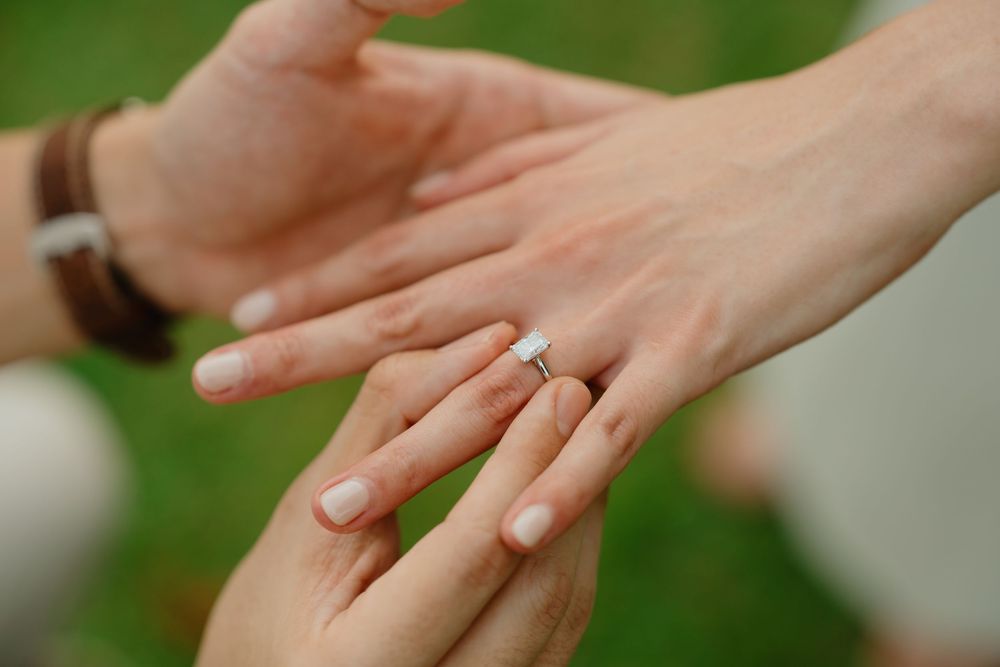 Close-up view of hands performing a gentle massage on another person's hand against a soft green background.