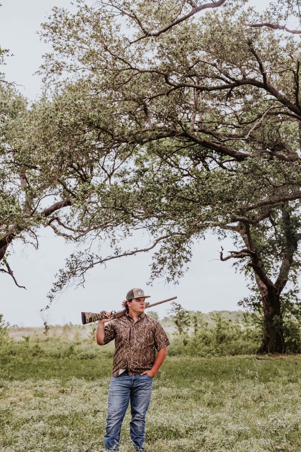 A scenic outdoor photo shoot in a grassy field with blooming trees in the background.