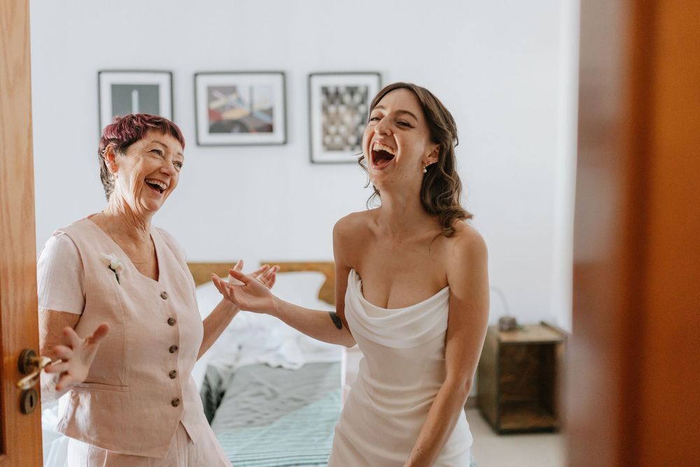 A group of people laughing together during a joyful moment in a bright white room.