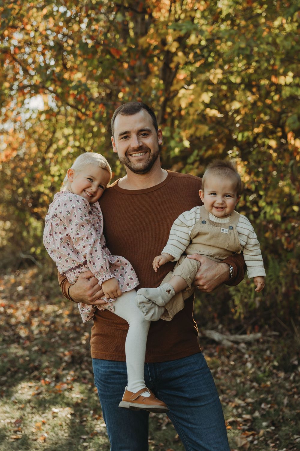 A joyful family moment captured in autumn with warm brown and golden tones in a natural outdoor setting.