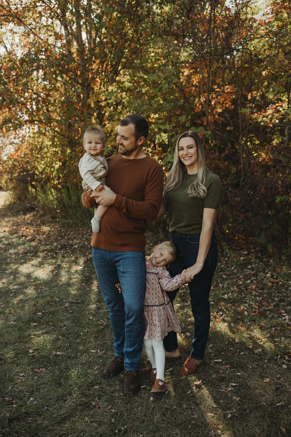 Family enjoying a fall day together outdoors among autumn trees and foliage.