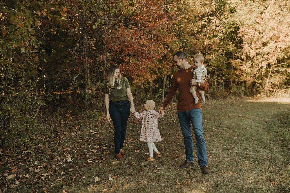 Family walking together on a wooded path during a fall photoshoot in nature.