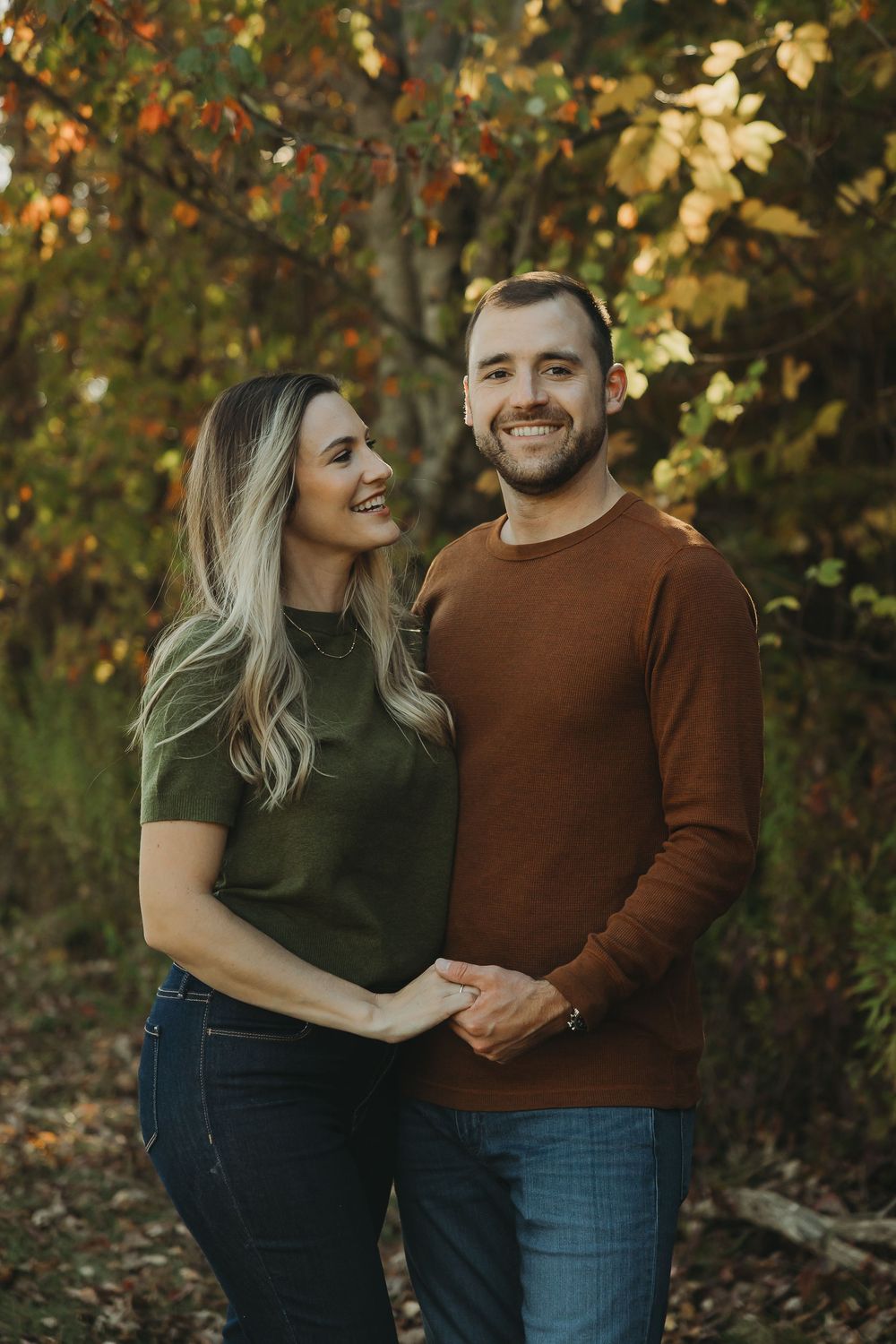 A couple shares tender moments together during an autumn photoshoot with colorful fall foliage in the background.
