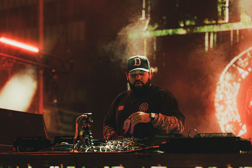 Electronic music performance setup with red and white lighting creating a moody atmosphere.