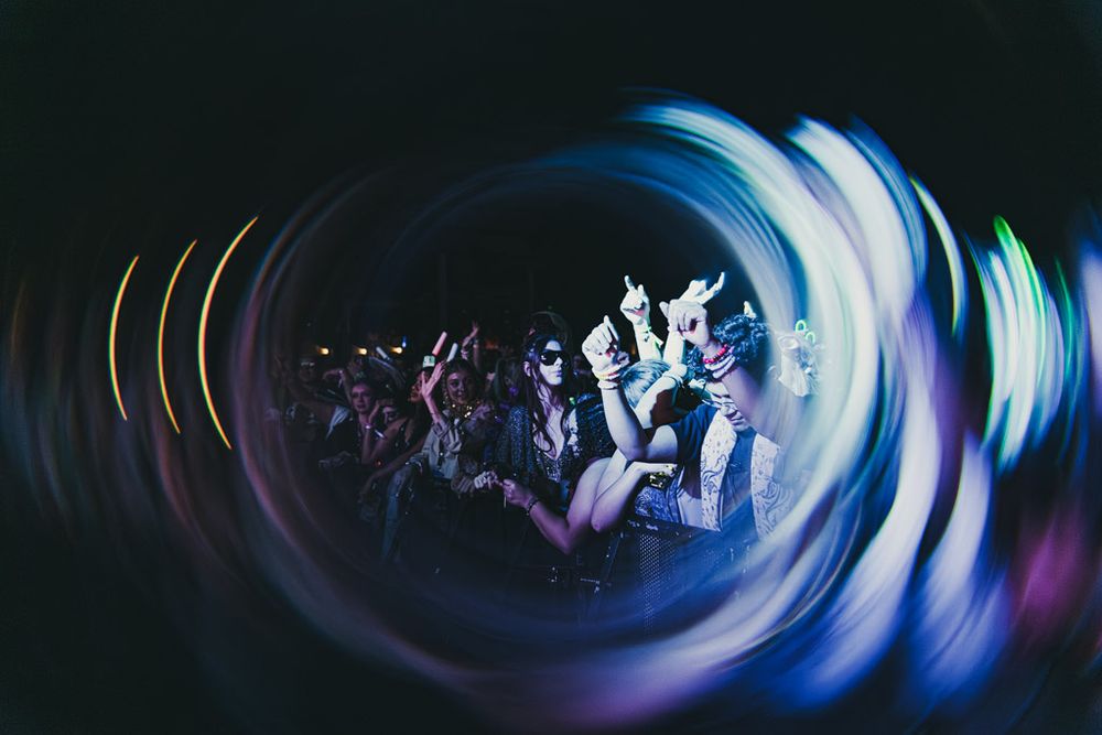 Long exposure shot shows blue and purple light trails creating spiral patterns in a dark space.