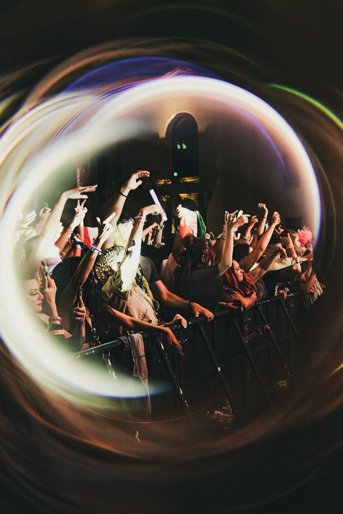 Concert crowd silhouettes captured through a fisheye lens with dramatic lighting effects.