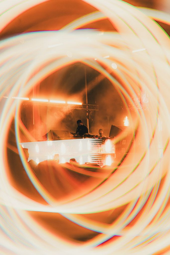 Warm-toned spiral light trails frame a dimly lit performance stage.