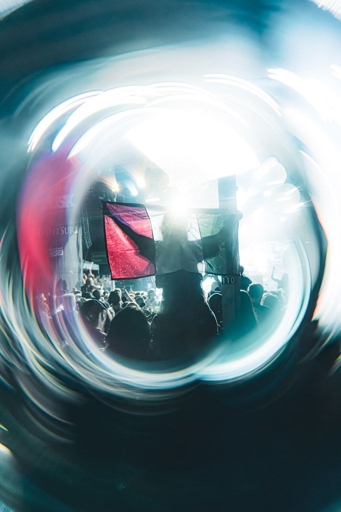 Abstract swirling light patterns in blue and red create a dynamic concert atmosphere.