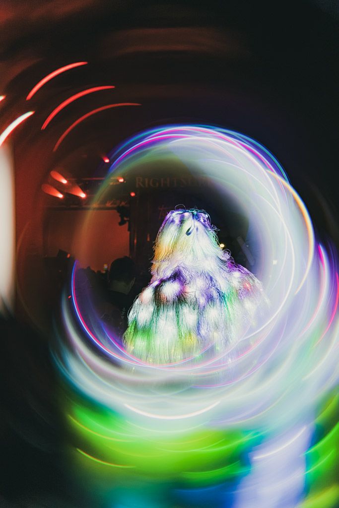 Swirling light trails in green and white create a spiral tunnel effect in low light.